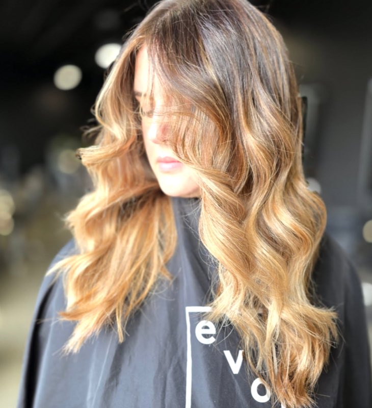 Hand-painted balayage on long wavy hair, finished with a warm golden toner